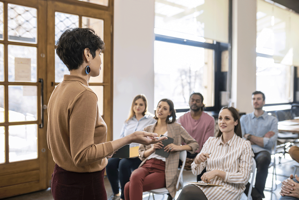 image of professional providing in-person training/professional development to a group of other professionals | Higher Ed Marketing & Student Search Services | enrollmentFUEL